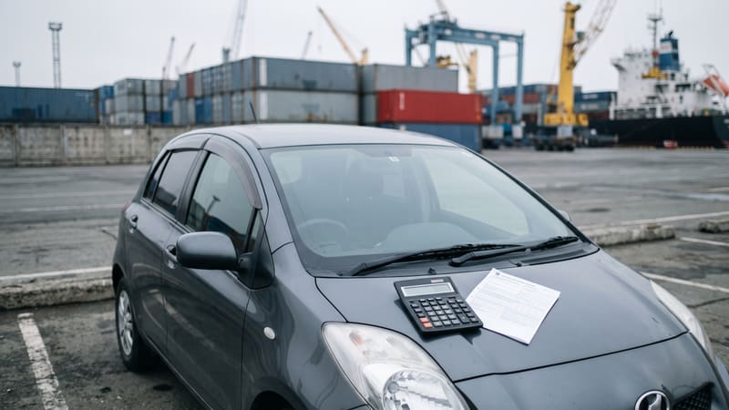 Компактный автомобиль из Японии на таможенном терминале Владивостока, на капоте калькулятор и декларация